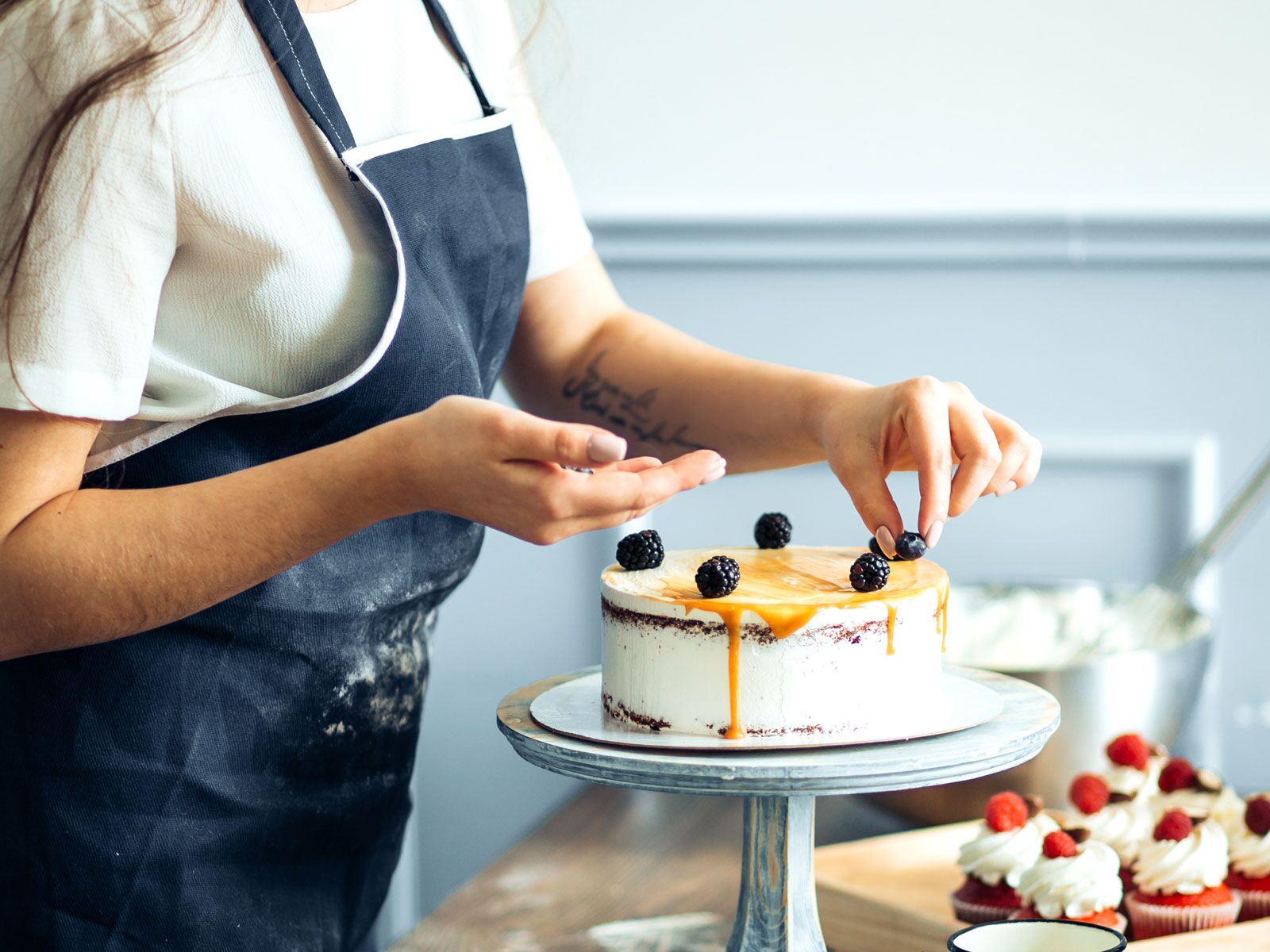 cake baker in blue apron decorating cake 