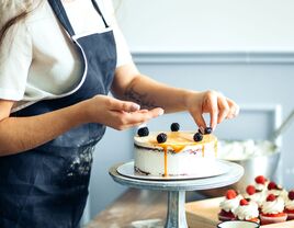 cake baker in blue apron decorating cake 