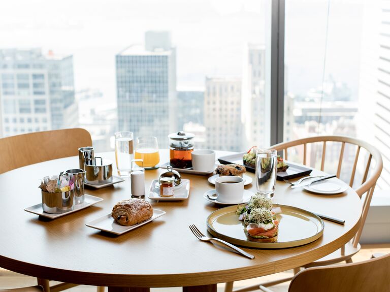 Room service breakfast spread on hotel room table placed by large window