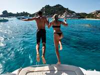 Newlywed couple jumping off boat into ocean on honeymoon