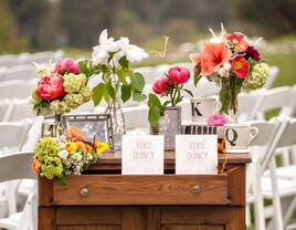 Outdoor wedding program table setup with family photos and flowers