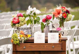 Outdoor wedding program table setup with family photos and flowers