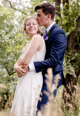 groom in blue suit hugging bride and kissing her on the head