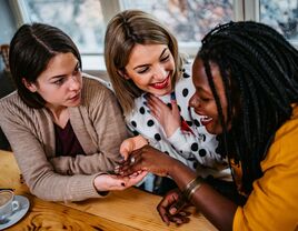 Two women congratulate their friend who just got engaged