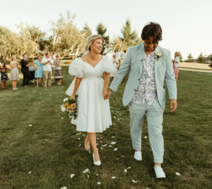 Couple holding hands and smiling at backyard wedding ceremony