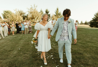 Couple holding hands and smiling at backyard wedding ceremony