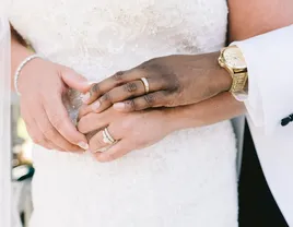 Close up of groom hugging bride form behind while wearing wedding rings