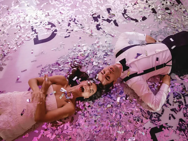 Couple laying in purple confetti, taylor swift themed wedding 