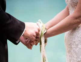 bride and groom performing handfasting ceremony at wedding