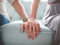 Couple holding hands on couch