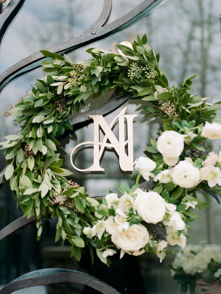 greenery eucalyptus wreath decorated with white flowers and couple's monogram in the center