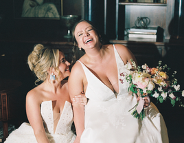 Two brides laughing together on their wedding day