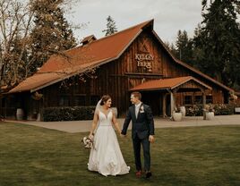 Couple holding hands outside the wooden barn venue at The Kelley Farm
