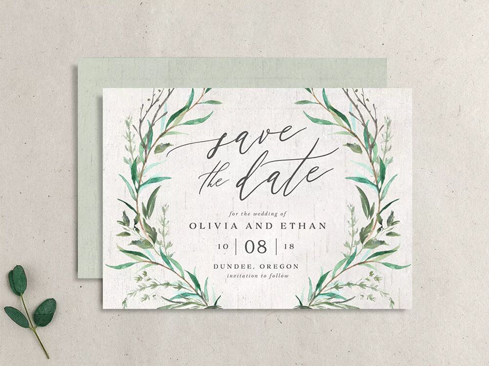 Green watercolor vines bordering 'save the date' in calligraphy type and event details in minimalist brown type