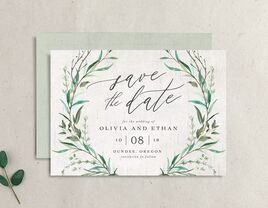 Green watercolor vines bordering 'save the date' in calligraphy type and event details in minimalist brown type