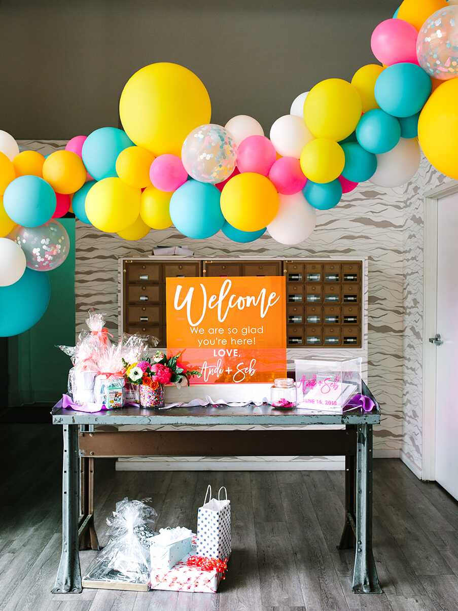 Bright yellow and teal blue balloon garland over a welcome table