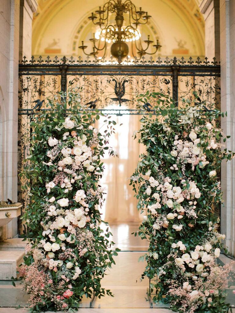 Dramatic lush floral bushes at wedding entrance