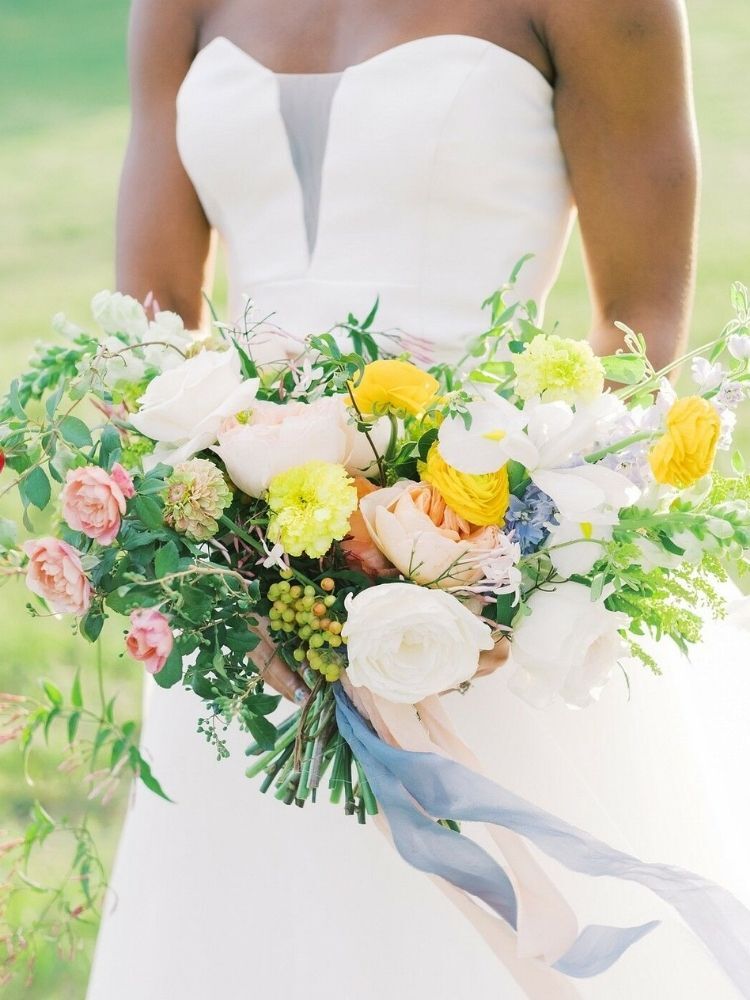 bride holding white-and-yellow wedding bouquet