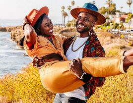 Couple laughing and posing beside ocean