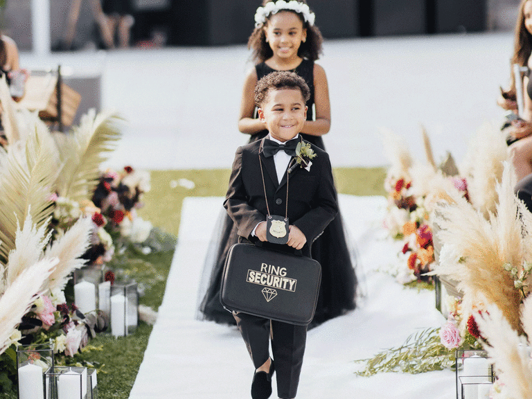 Ring bearer smiling and walking down the aisle.