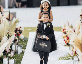 Ring bearer smiling and walking down the aisle.