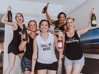 A bachelorette party wearing slogan shirts and holding bottles of champagne