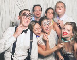 bride, groom and wedding guests in a photo booth at the reception