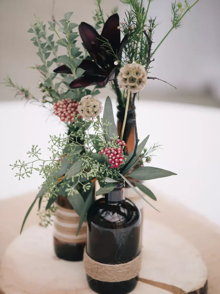 Scabiosa Pod and Eucalyptus Centerpieces in Twine-Wrapped Brown Bottles