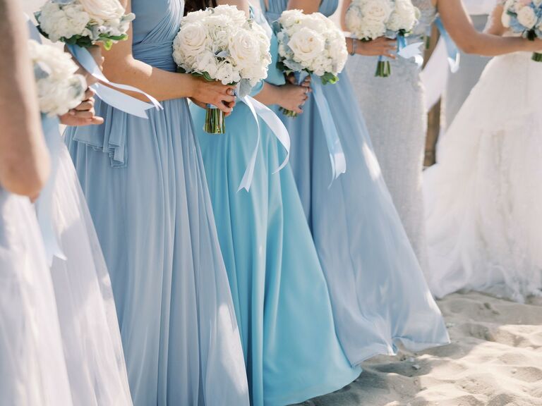 Bridesmaids wear dresses in various shades of light blue. 