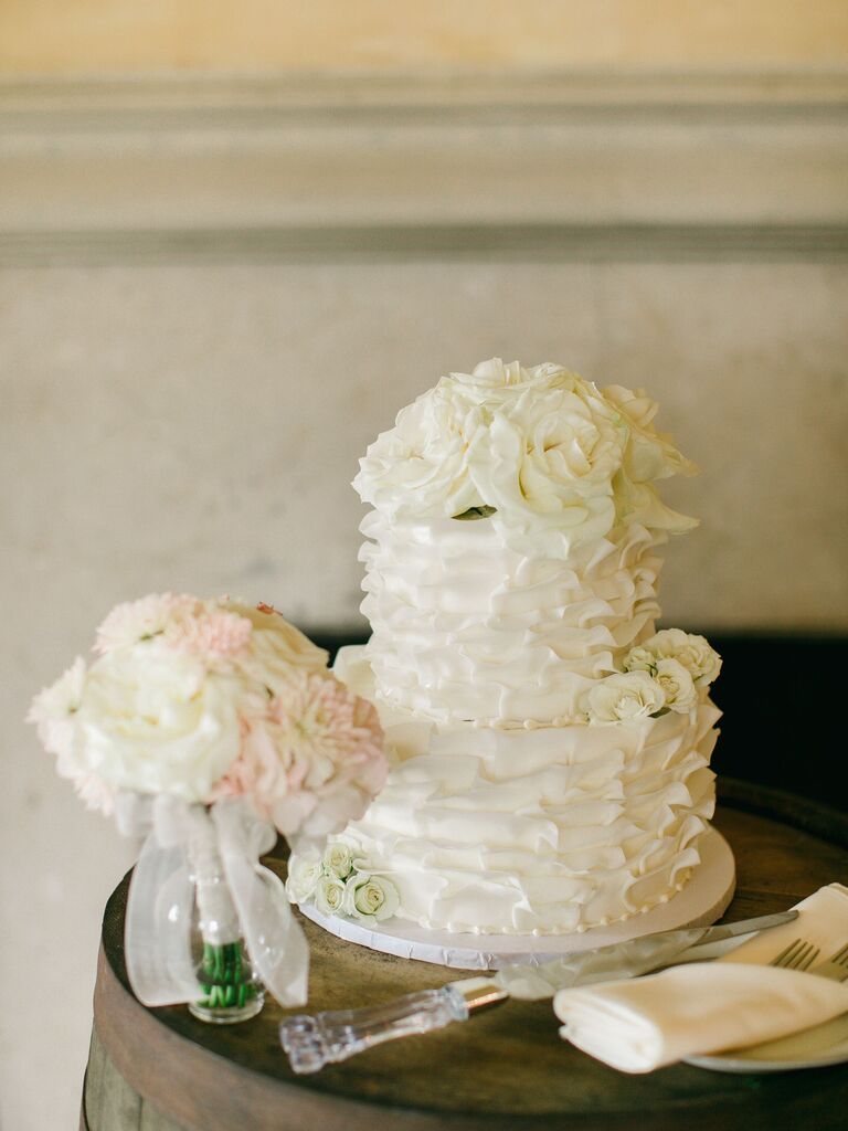 simple two tier wedding cake with white textured buttercream and white roses on top tier