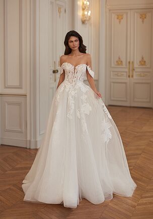 The Moonlight Collection J7003 wedding dress is a regal A-line gown in layers of tulle and sparkle tulle, featuring a strapless sweetheart bodice, basque waist, and shimmering lace appliqués for a romantic, princess-inspired look. Finished with a voluminous skirt, chapel train, and detachable swag sleeves, this ivory or ivory/sand/light nude design offers dramatic elegance with versatile styling.