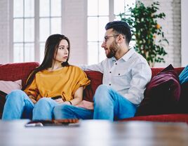 woman and man sitting on couch having a serious conversation