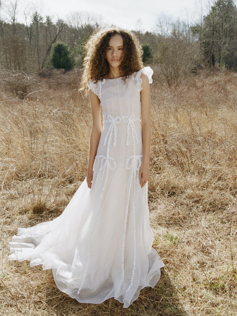 model wearing a-line wedding dress stands in open field