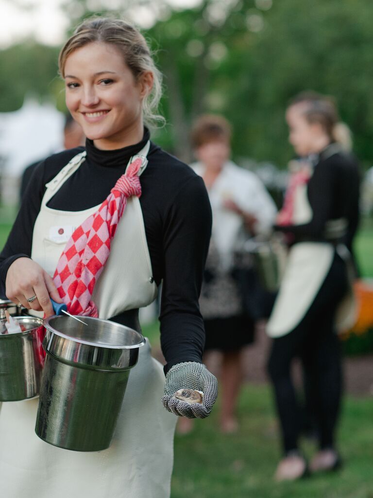 waitress holding oyster shucking buckets and tools during cocktail hour