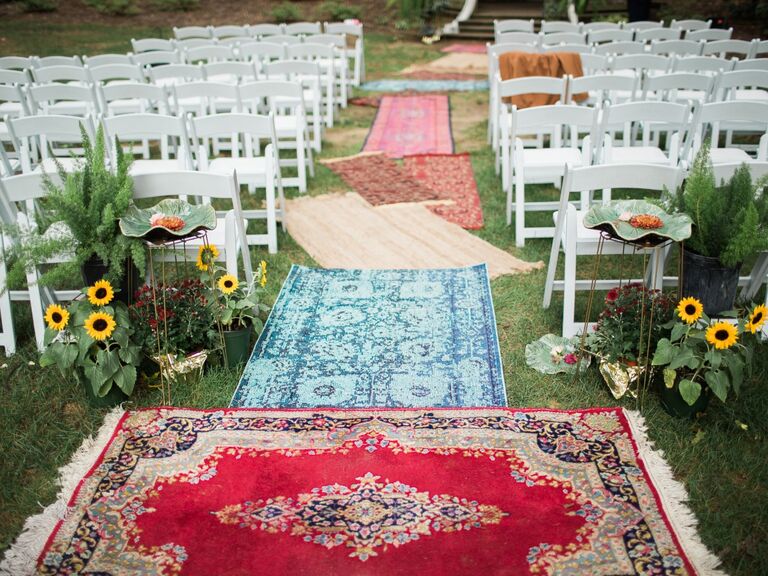Aisle lined with mismatched colorful rugs. 