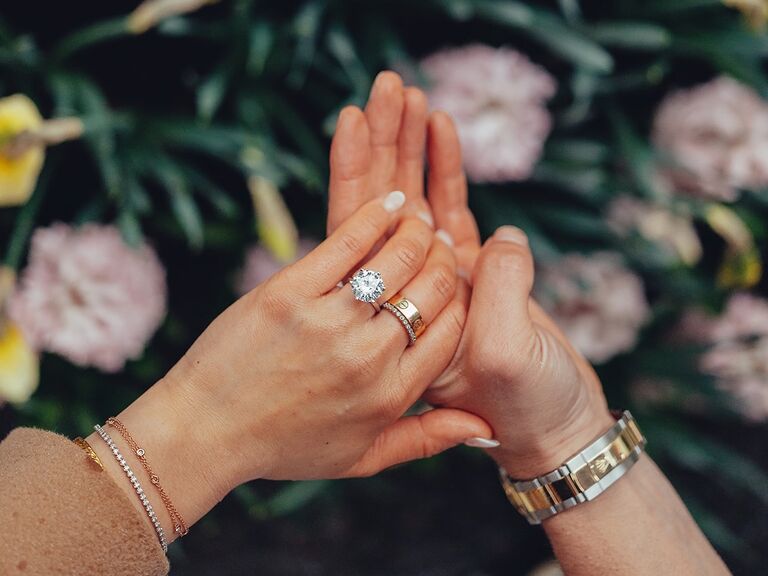 engagement announcement photo with couple holding hands and bride wearing round diamond engagement ring