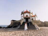 Couple on the Miramar beach with the famous Capela da Senhora Pedra for their wedding
