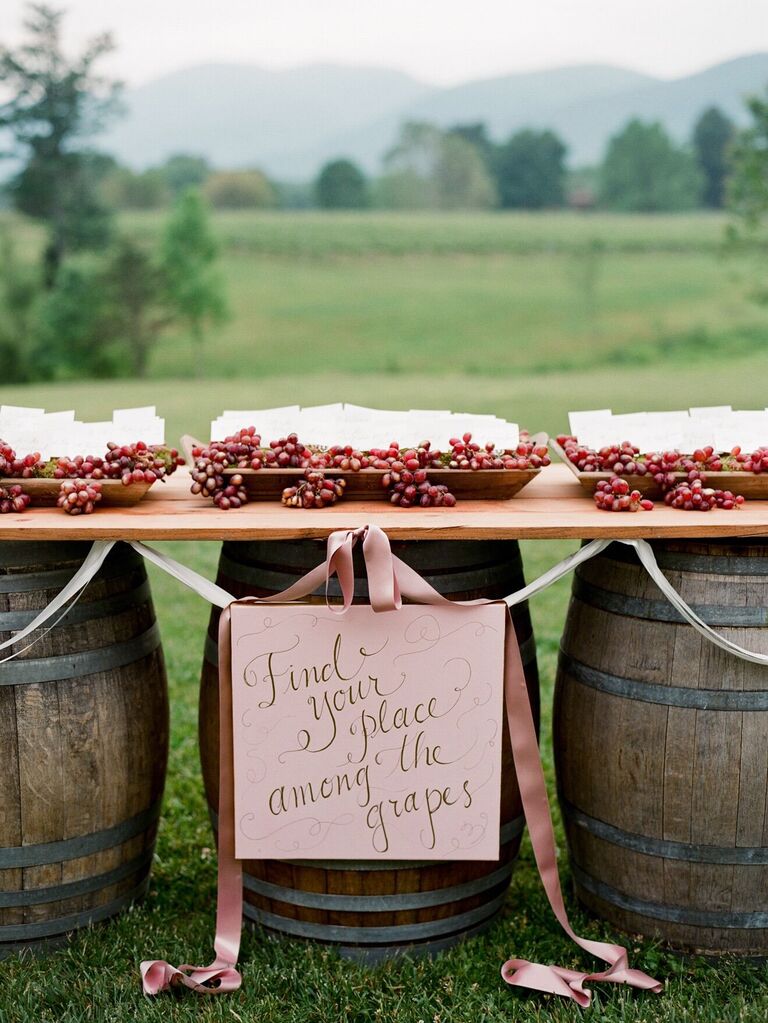 A festive grape-decorated seating chart at a vineyard wedding