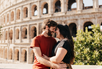 Couple smiling in front of The Colosseum in Rome