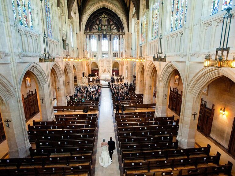A couple walks down the aisle of a Catholic cathedral.