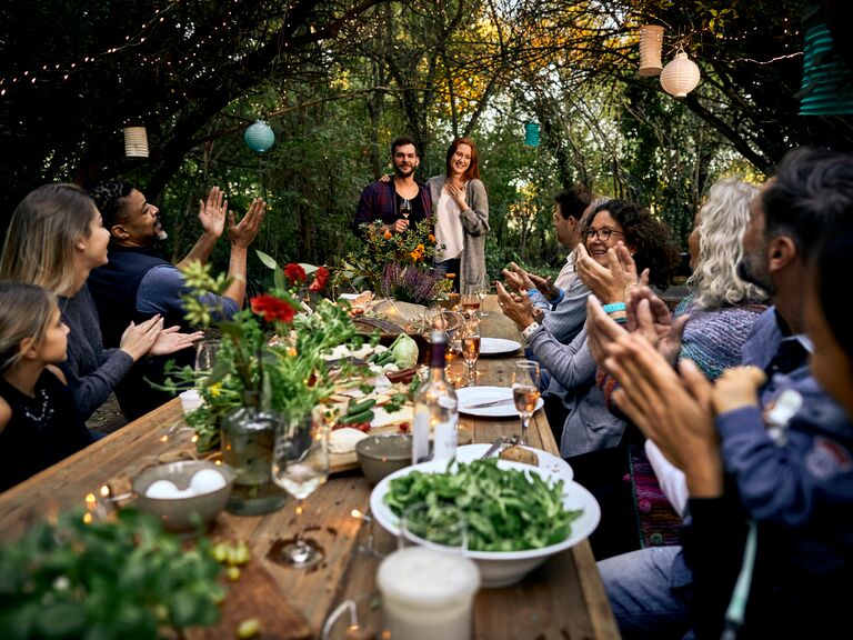 friends celebrating a couple at a big dinner party in a garden