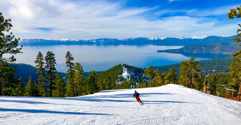 lake tahoe skiing with lake in the backdrop and skier lone and happy going down the trails