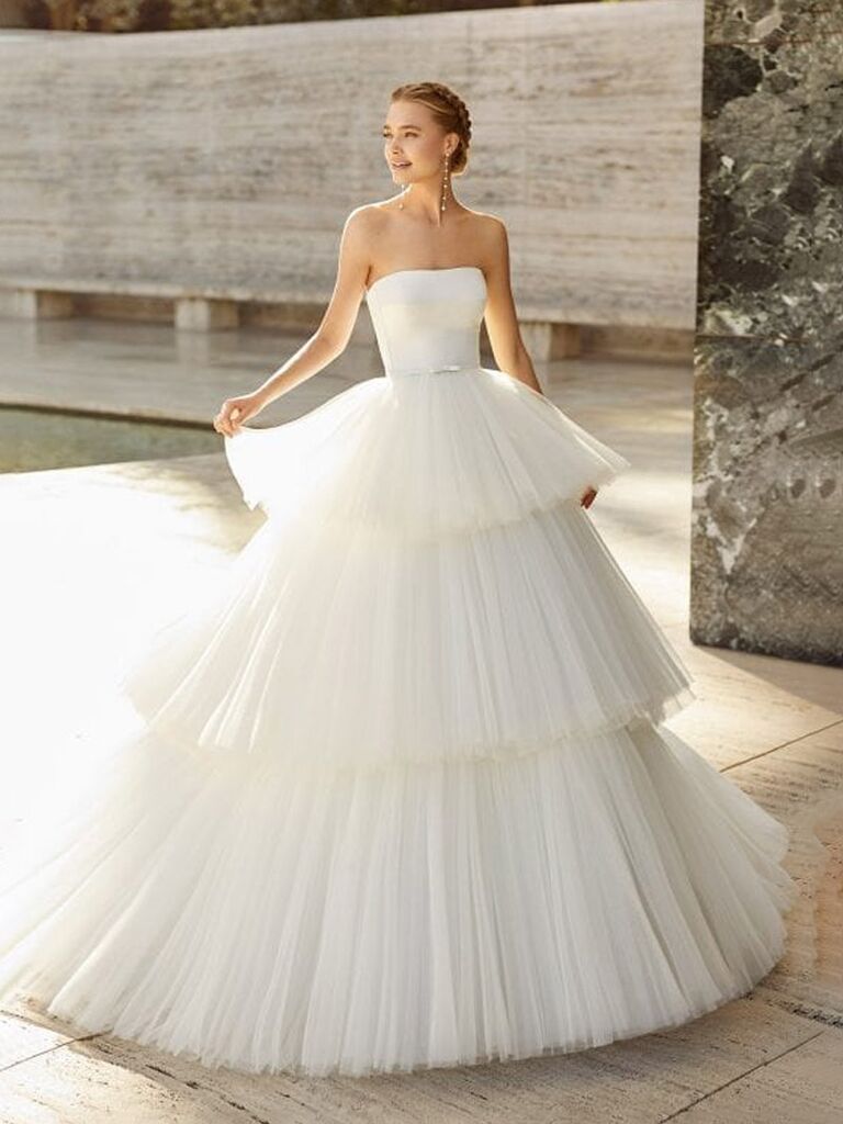 white lily couture rosa clará plain white strapless wedding dress with rounded neckline bow belt and tiered puffy tulle ball gown skirt