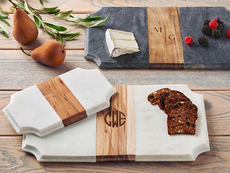 White marble charcuterie board with wooden strip through center and monogram