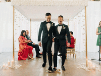 Grooms hold hands while doing the breaking the glass Jewish tradition. 