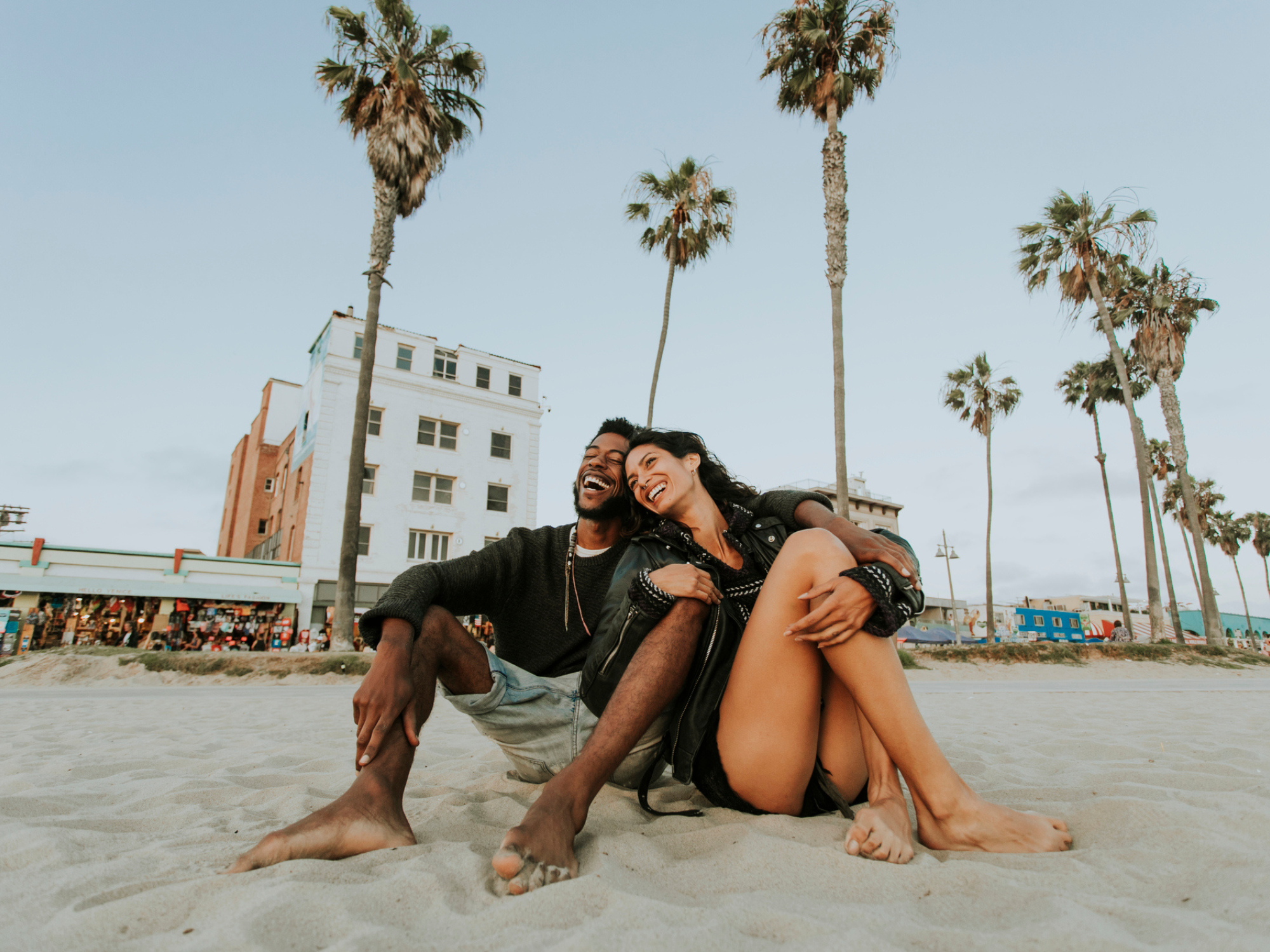 Couple smiling and sitting on beach together in Los Angeles