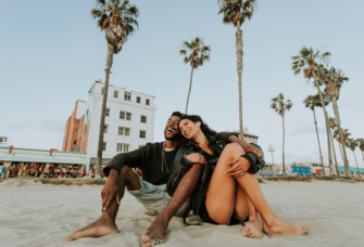 Couple smiling and sitting on beach together in Los Angeles