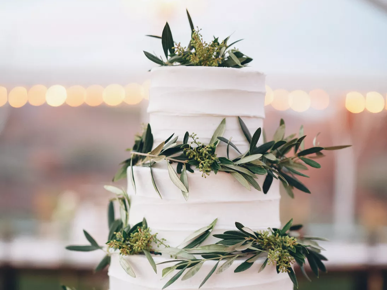A white wedding cake decorated with olive leaves