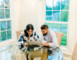 Couple sitting at kitchen table writing vendor review on laptop