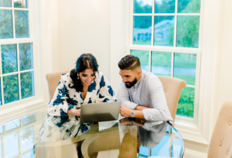 Couple sitting at kitchen table writing vendor review on laptop